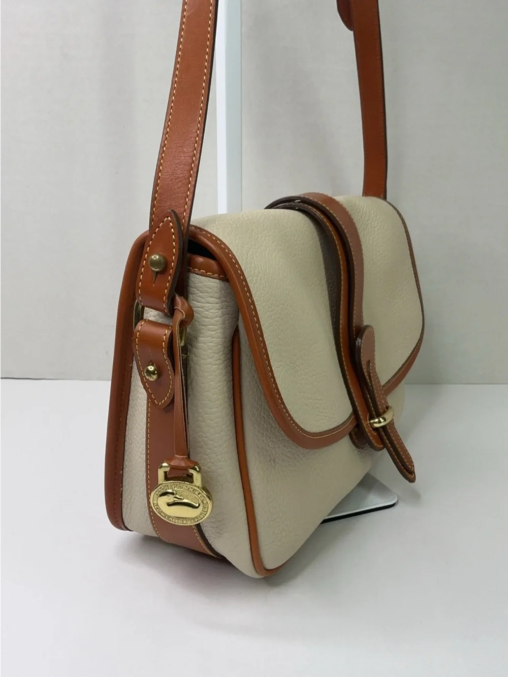 Dooney & Bourke cream and tan pebbled leather saddle bag